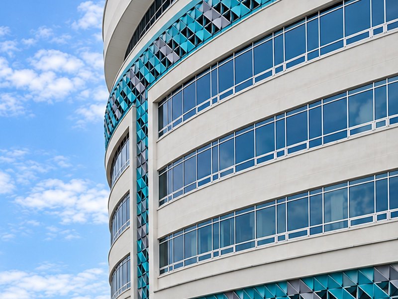 Edificio curvo con ventanería y paneles de color turquesa